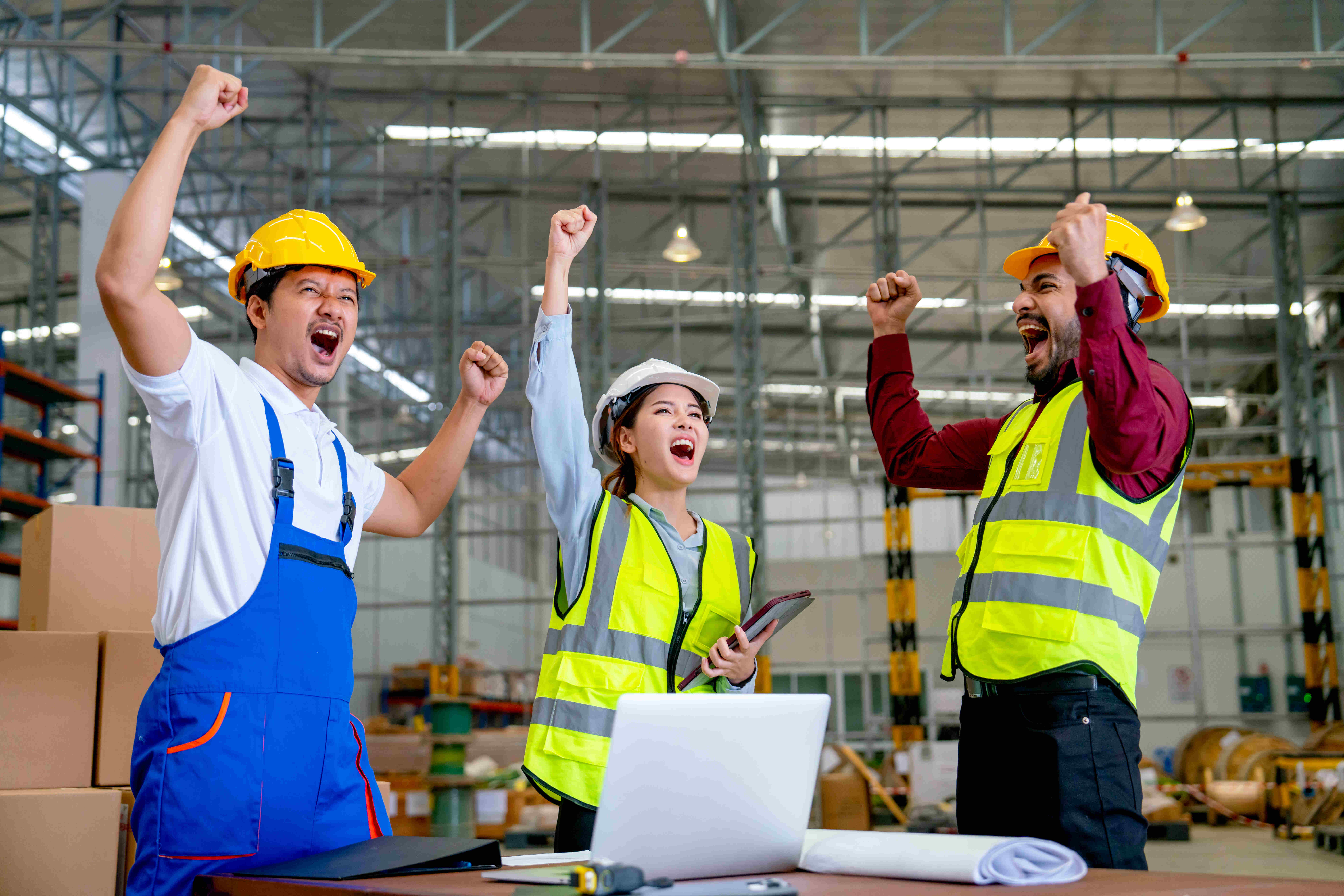 Group of Asian warehouse worker raise hands and action of very happy from successful of their project and stay in workplace with several tools on table.