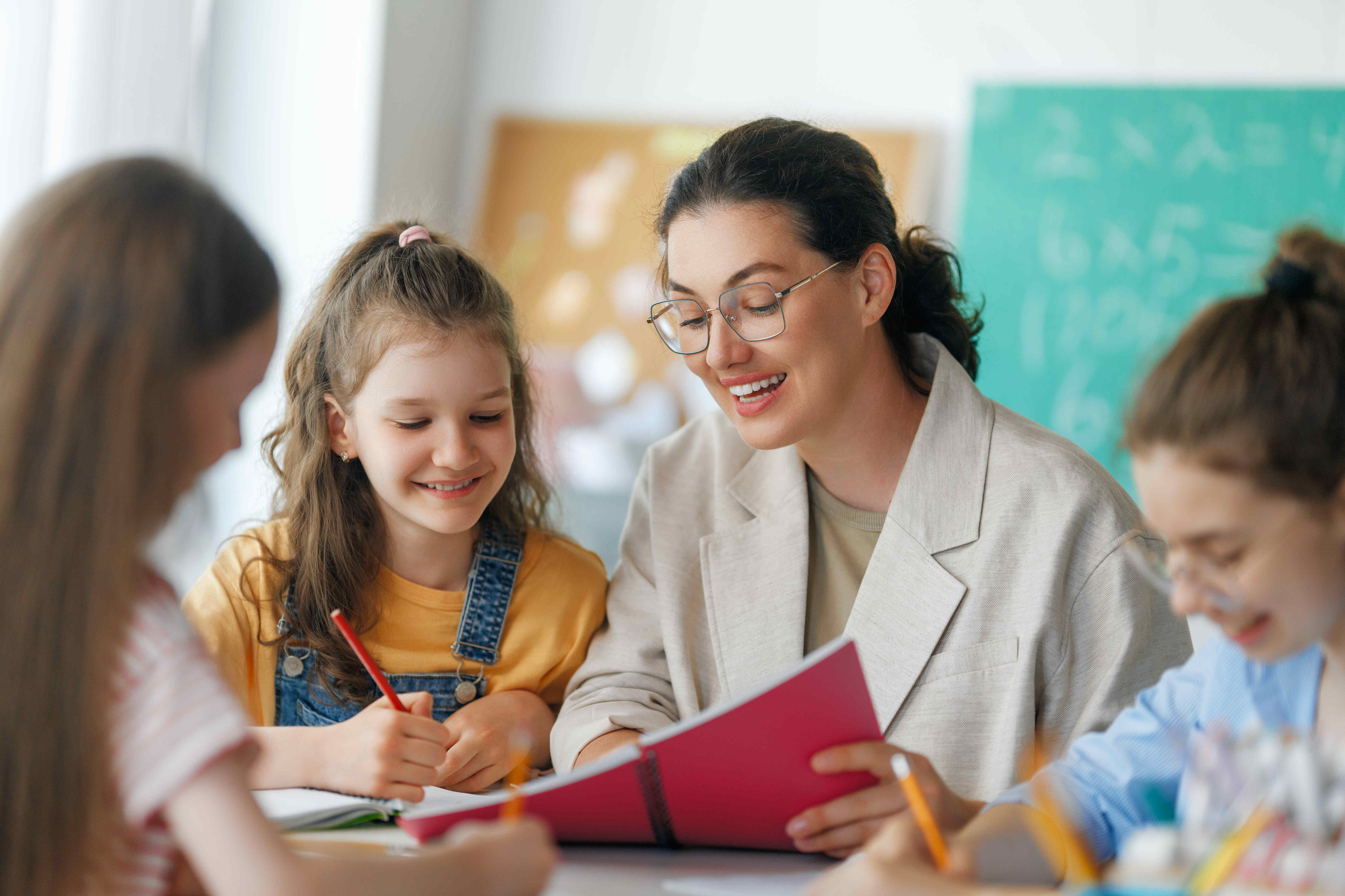 Happy kids and teacher at school. Woman and children are working in the class.